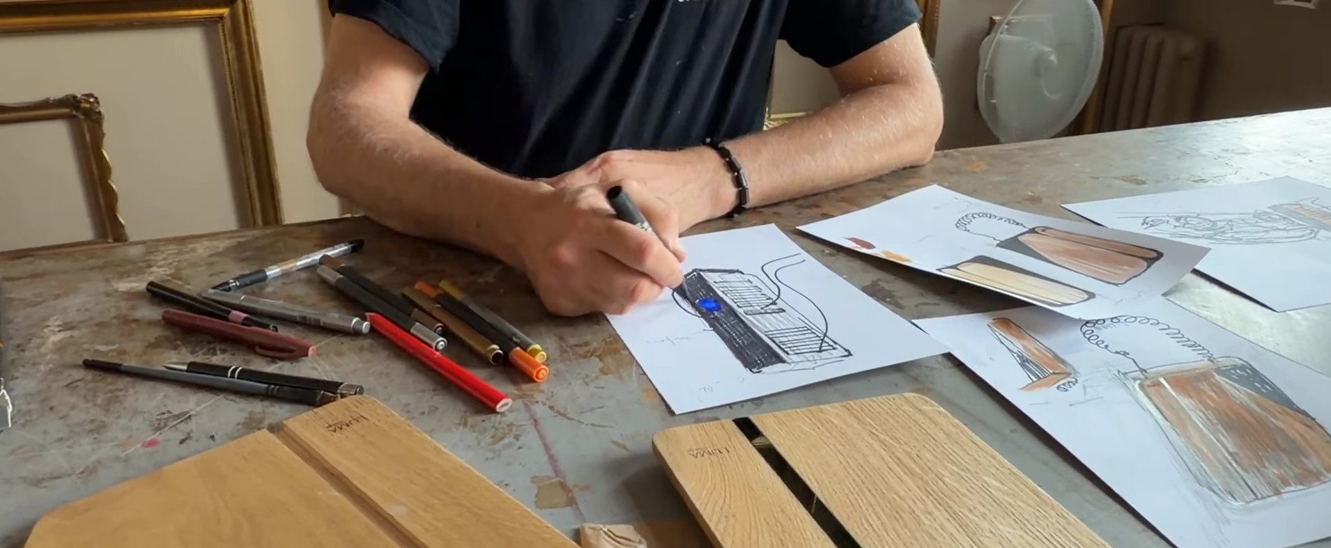 Projektant szkicujący front LUMA Wallbox AC ręcznie, obok próbki paneli z naturalnego drewna